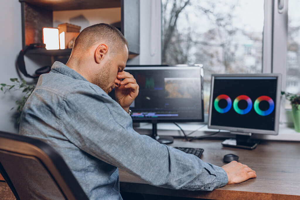 man sits at pc and has headache