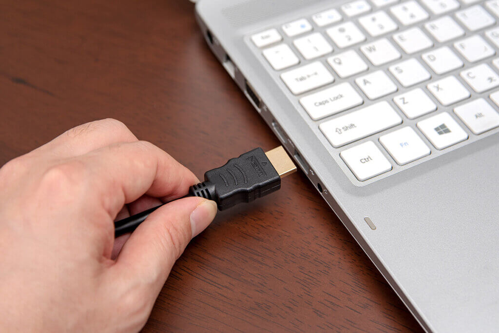 person plugs hdmi cable in a laptop
