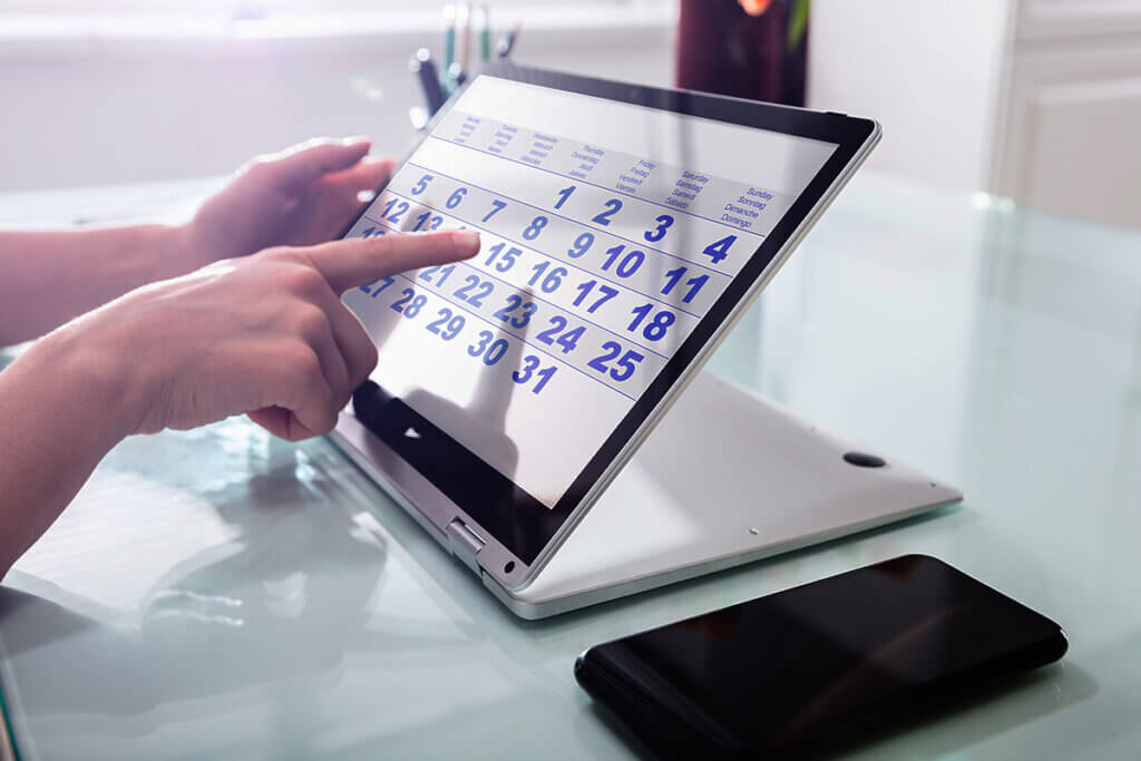 person with laptop looks at calendar