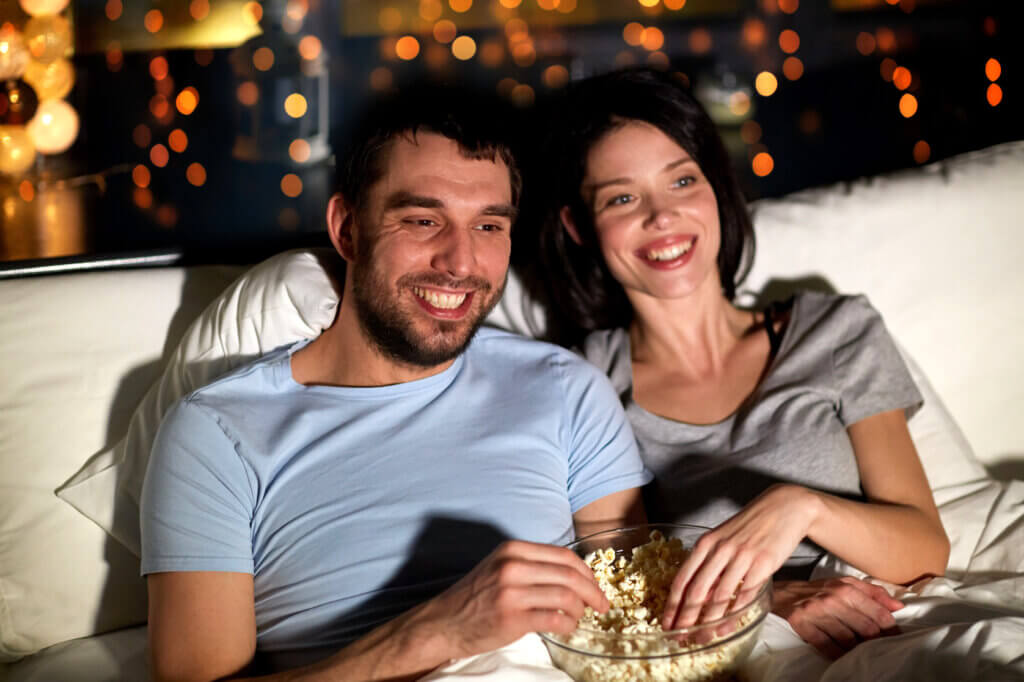 couple sits on sofa watching tv