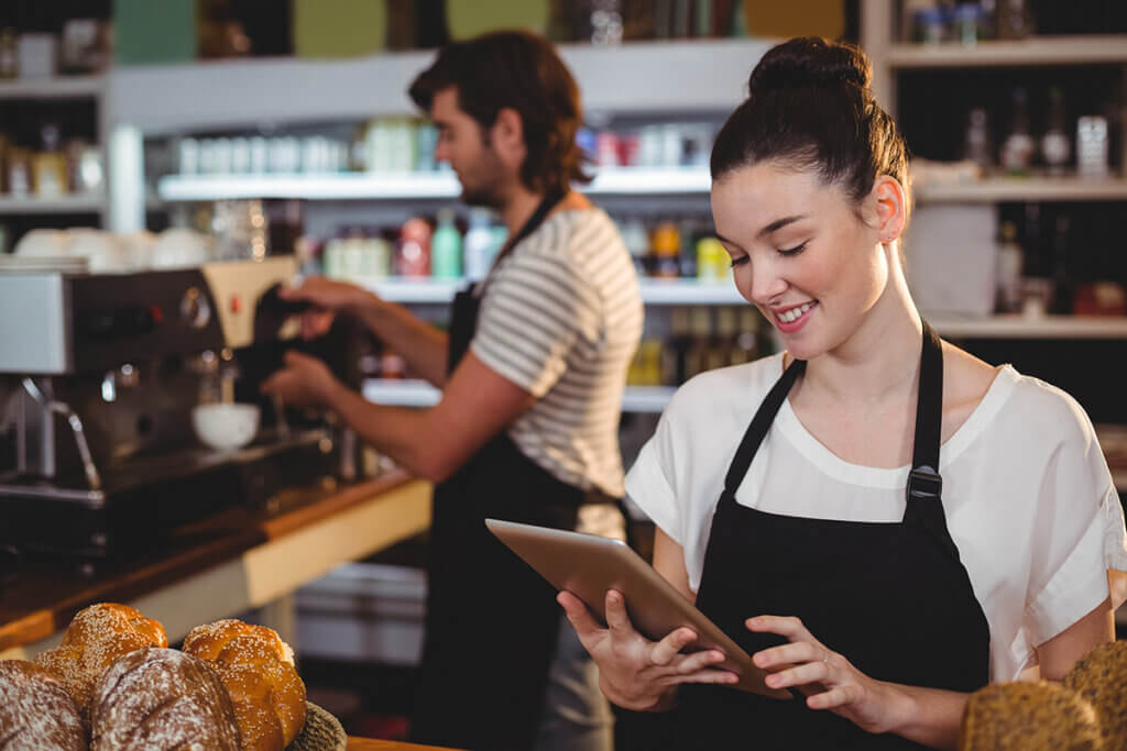 Female waitress in a café holds a tablet in her hand