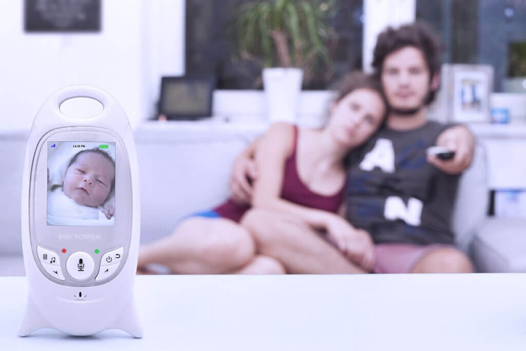 young couple sitting on sofa with babyphone