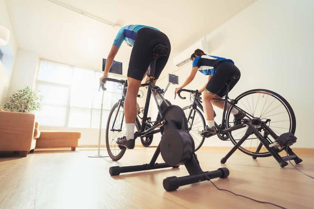 two people exercising together on roller trainers in the living room
