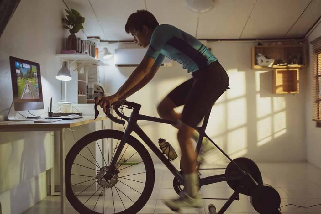man trains with bicycle roller trainer around looking at a screen