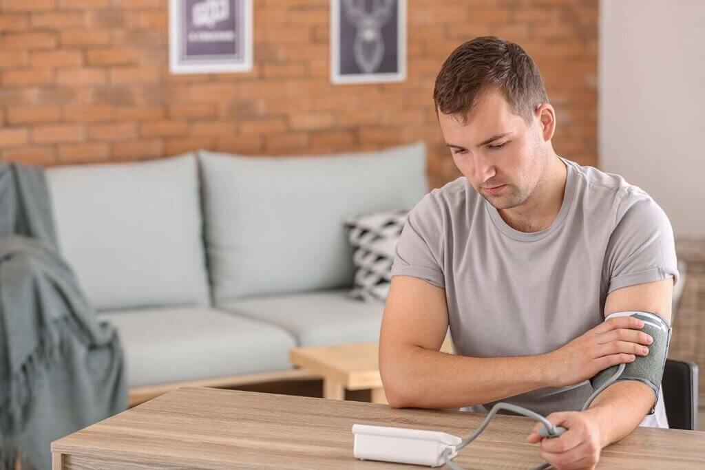 young man measures blood pressure with a device