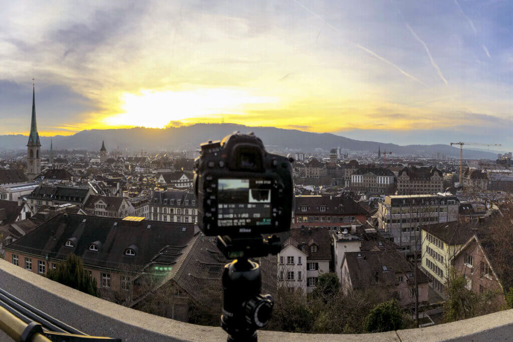 Bridge camera on a tripod taking a panorama shot of a city.