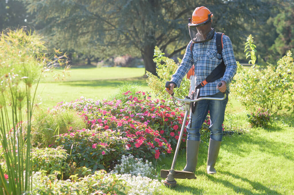 man trims the grass in the garden