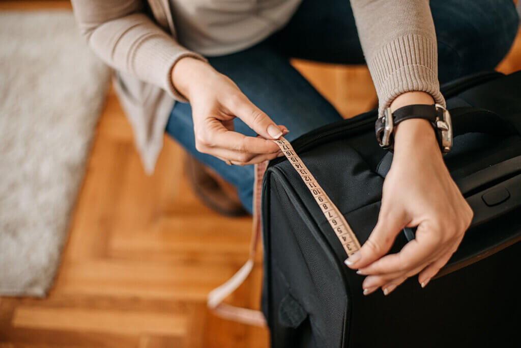 Woman measures suitcase