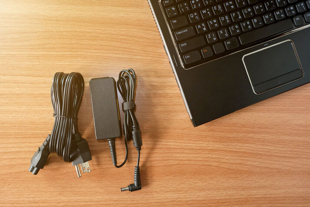 charger and laptop lie on a wooden table