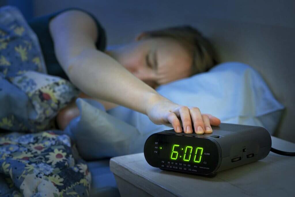 clock radio woman switches alarm off in the morning