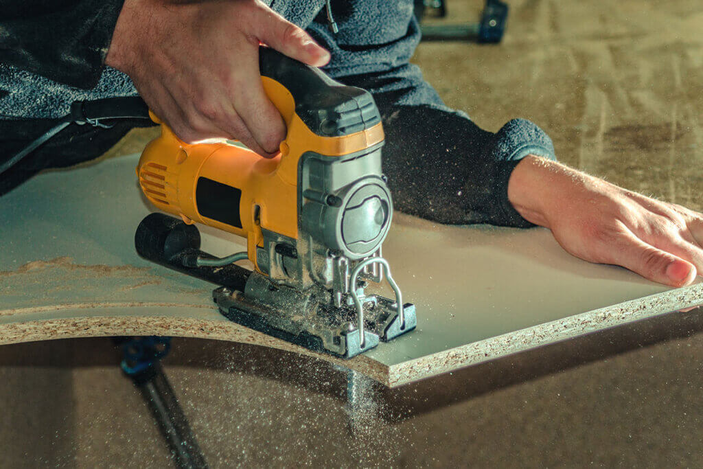 Cordless jigsaw cutting through a board