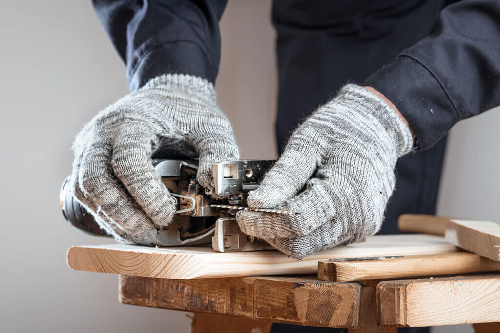 Person with woolen gloves changes blade of cordless jigsaw