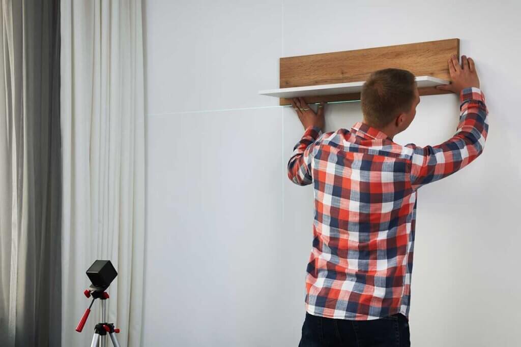 man brings shelf into living room