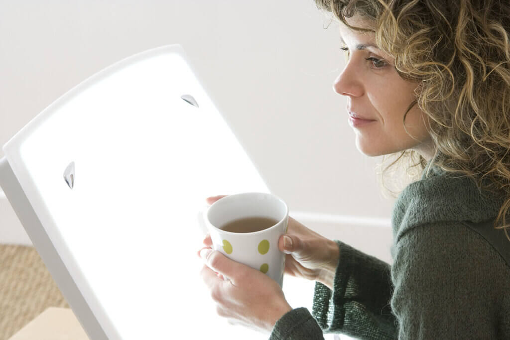 woman sits befor lamp drinking tea