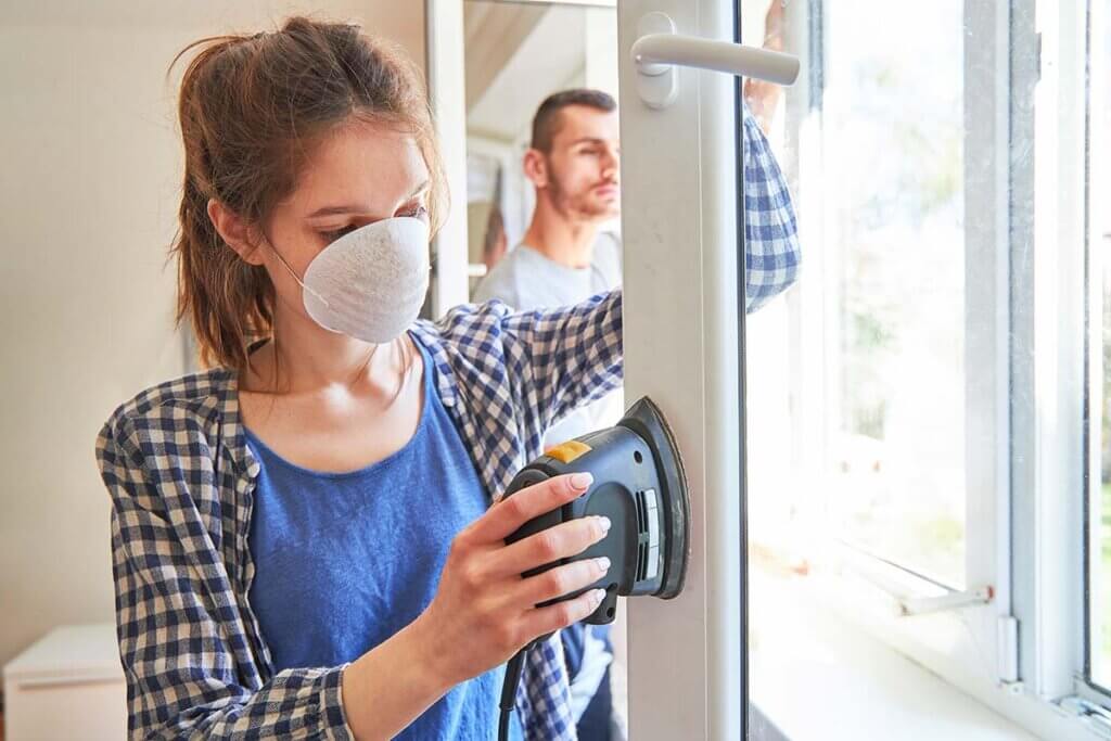 Multi-sander woman sanding down window frames