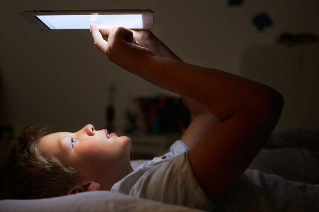  boy lying in bed and reading on an ebook reader