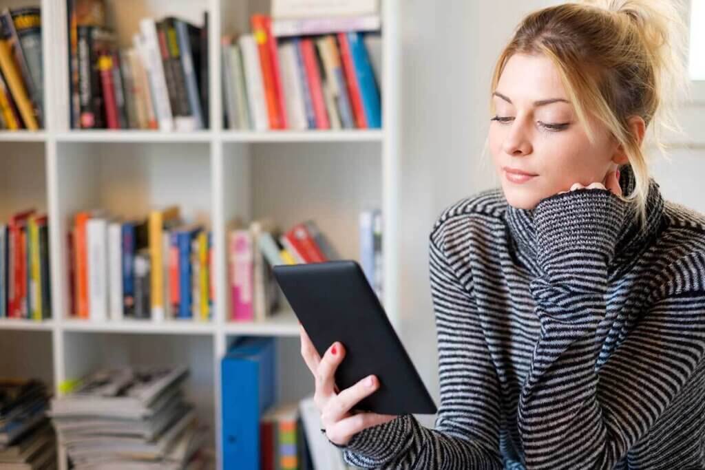 woman sitting in her room with an ebook reader in her hand