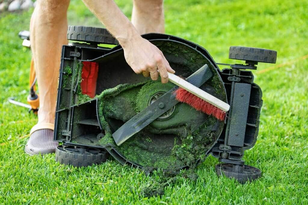 man cleans mower