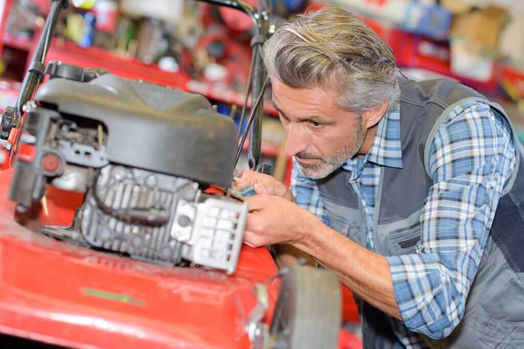 man repairs lawn mower