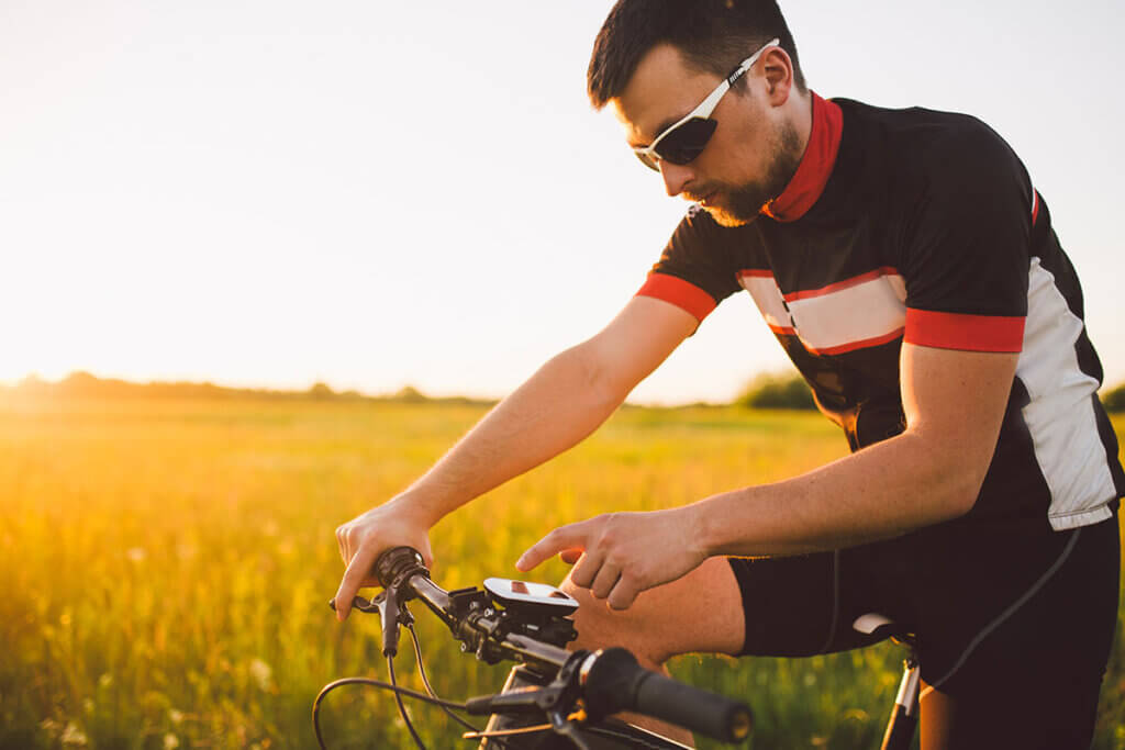 young cyclist in the field operates navi