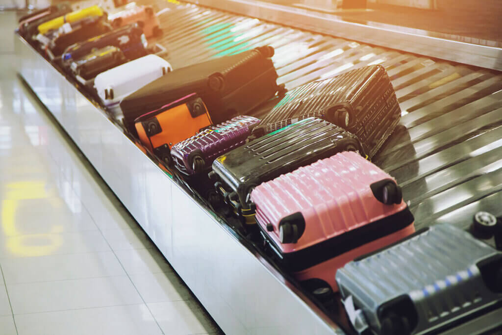 Several hard-sided suitcases lie on parcel conveyor belts at the airport
