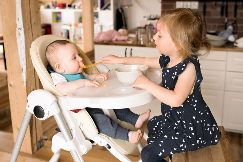 girl feeds little brother