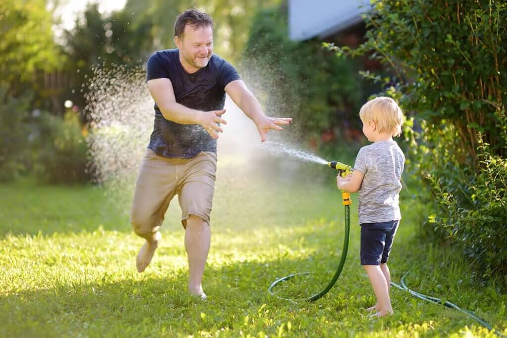 Child splashes father with garden hose