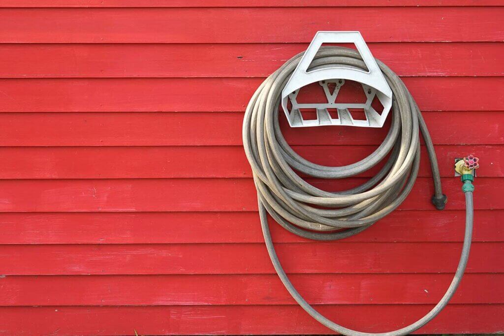 Hose holder including hose on house wall