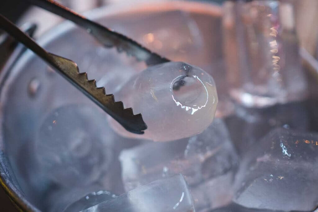ice cubes in the ice bucket are removed with tongs