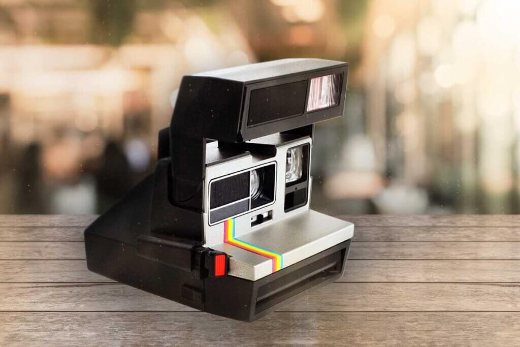 black instant camera stands on wood underground