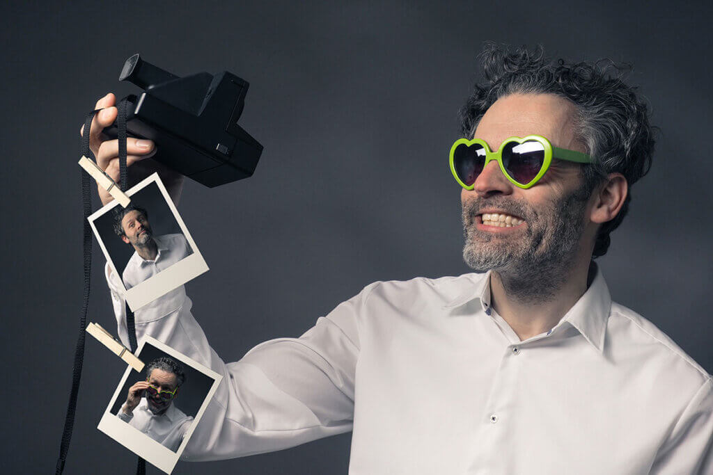 man with an instant camera takes selfies
