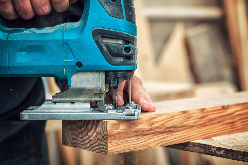 man saws with jigsaw wood beams