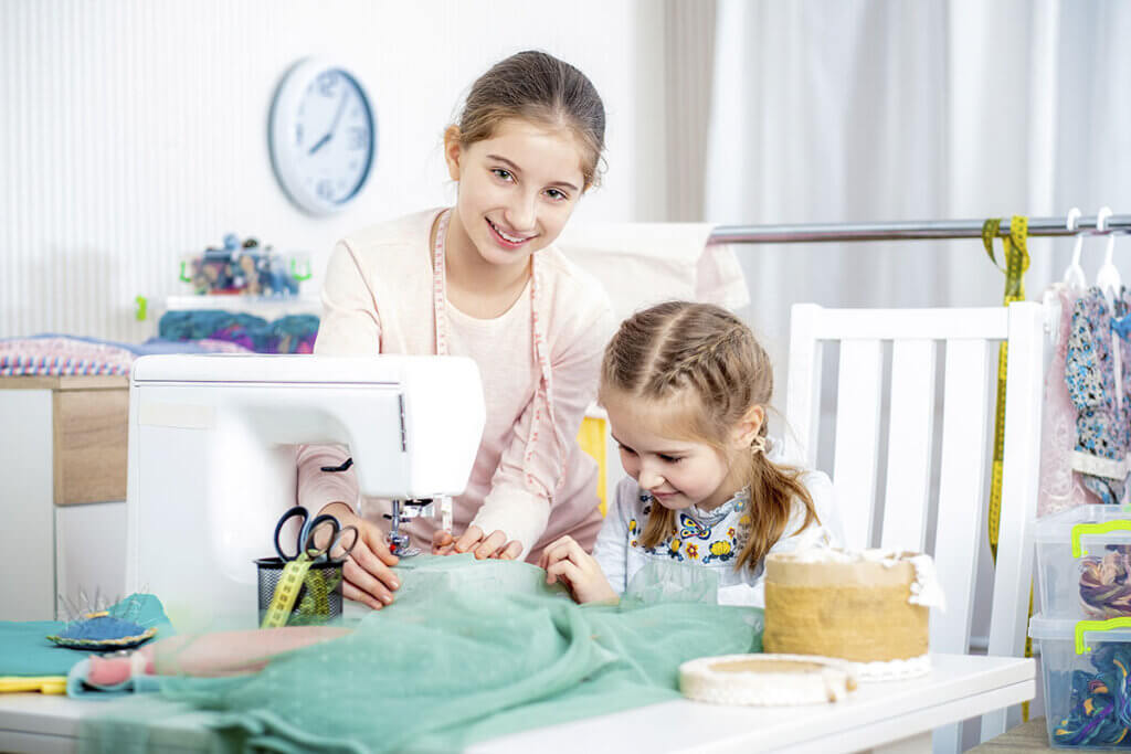 Siblings sew with a child's sewing machine