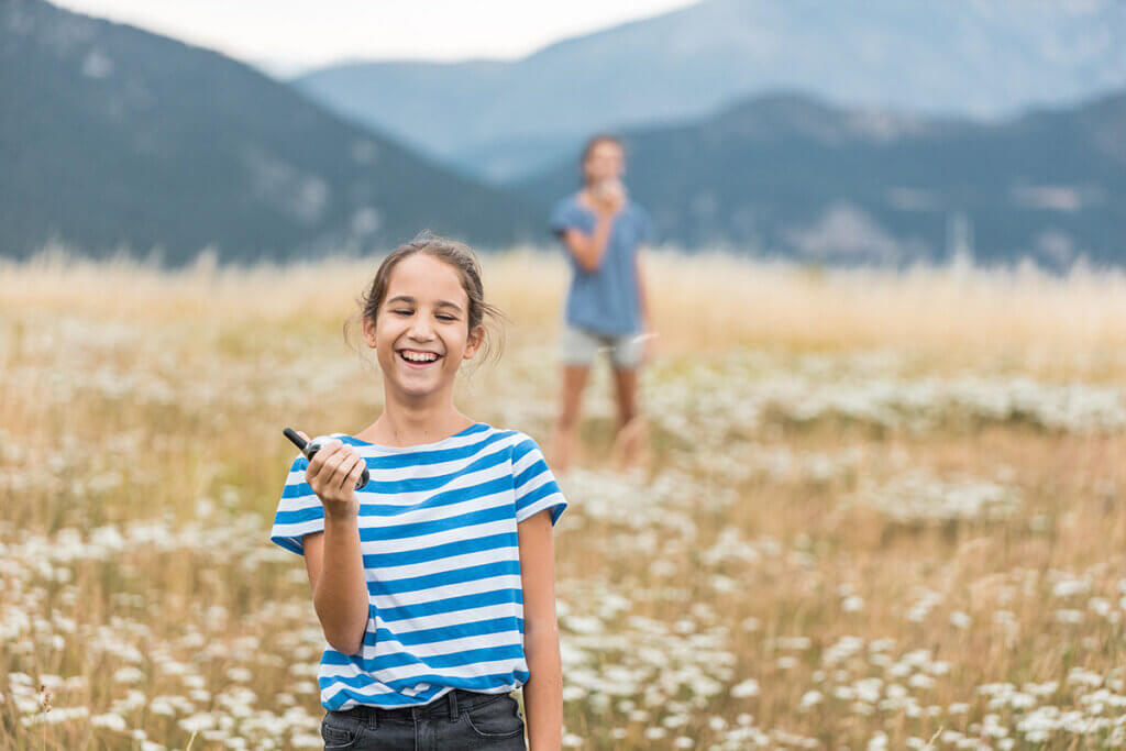 Two siblings playing with walkie-talkies outdoors