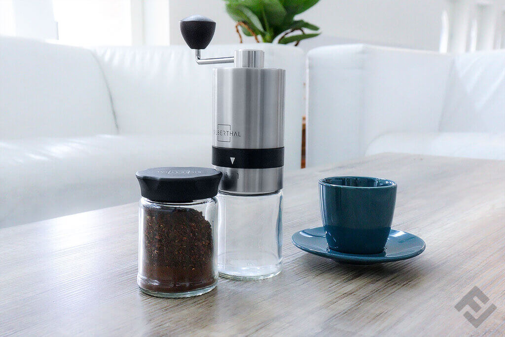Silberthal manual coffee grinder with replacement glass and a cup on a table
