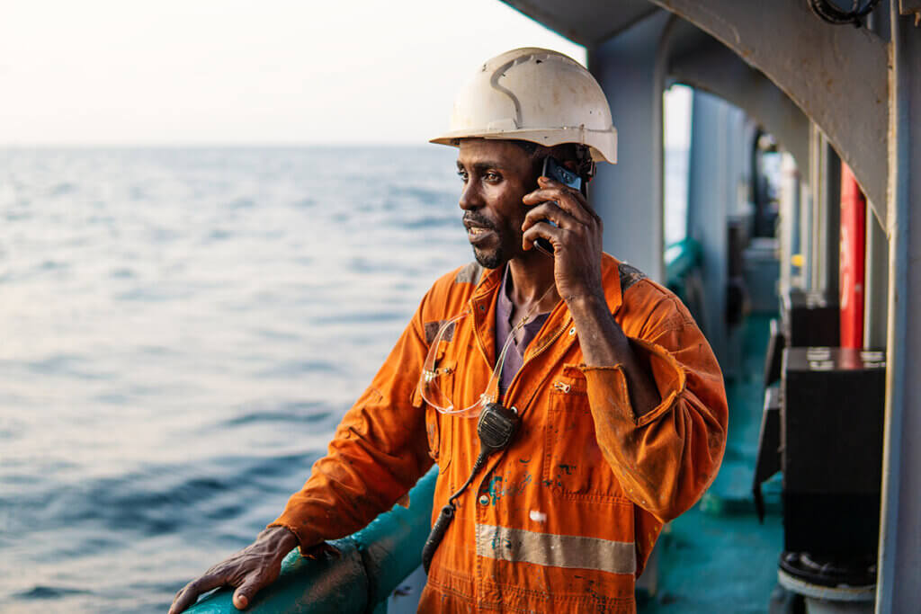 man on cargo ship using mobile phone