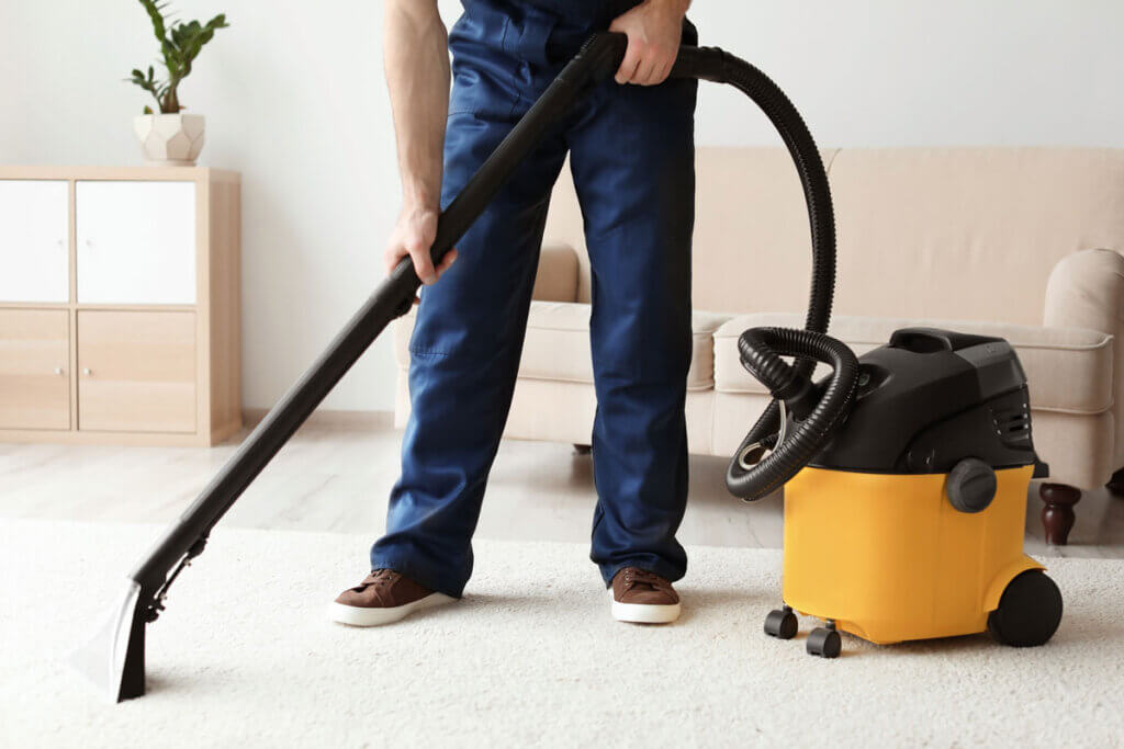 man vacuums carpet in living room