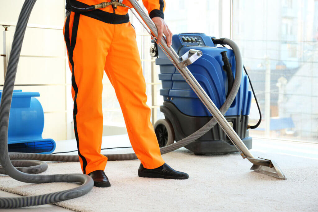 man vacuums floor with large appliance