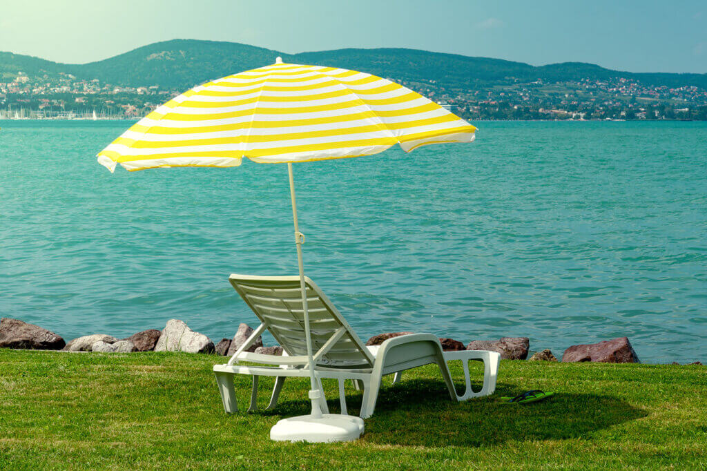 Lounger and parasol on the lawn by the sea