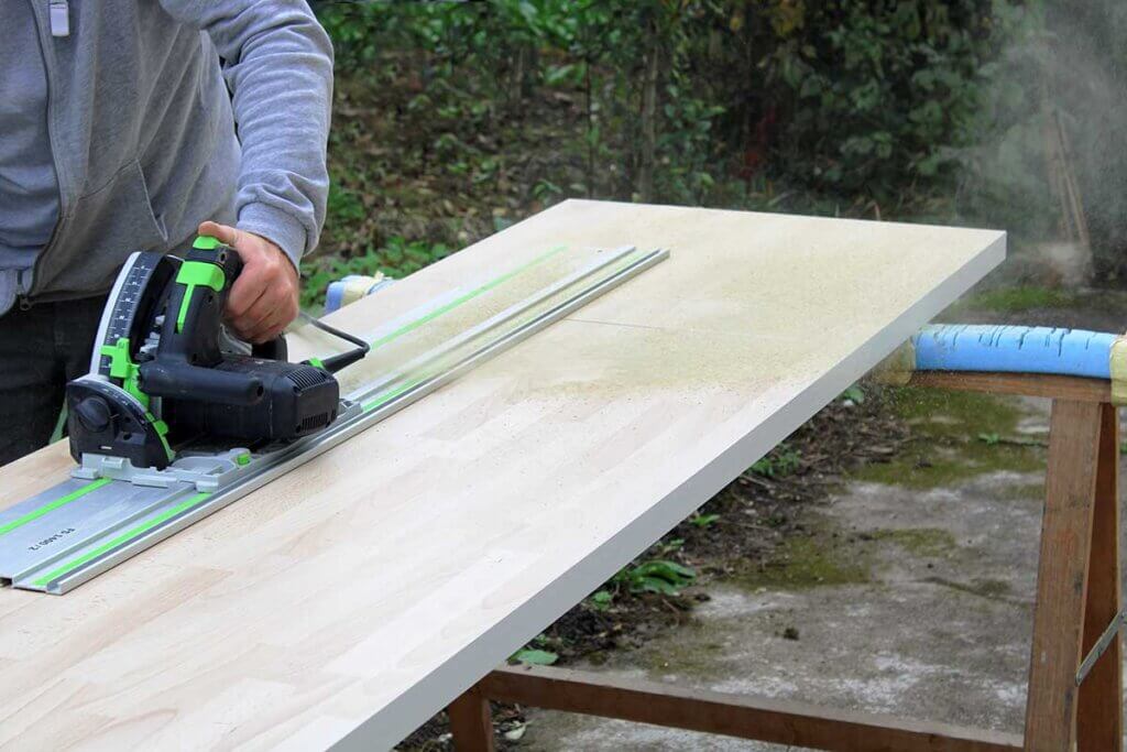 man works on thick board with plunge saw