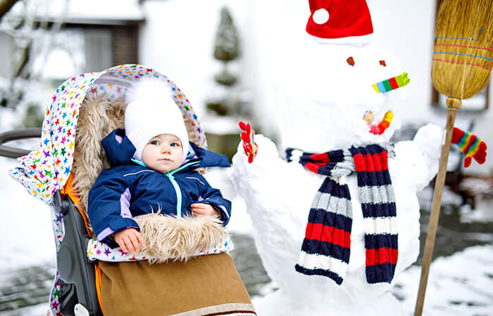 baby in pram next to snowman