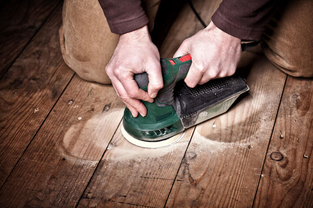 Orbital sander sanding a wooden floor