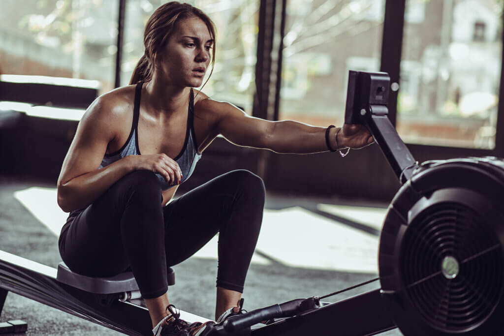 woman in studio using the rowing gear