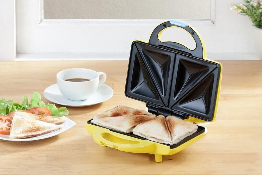 sandwich maker on breakfast table with sandwiches and coffee