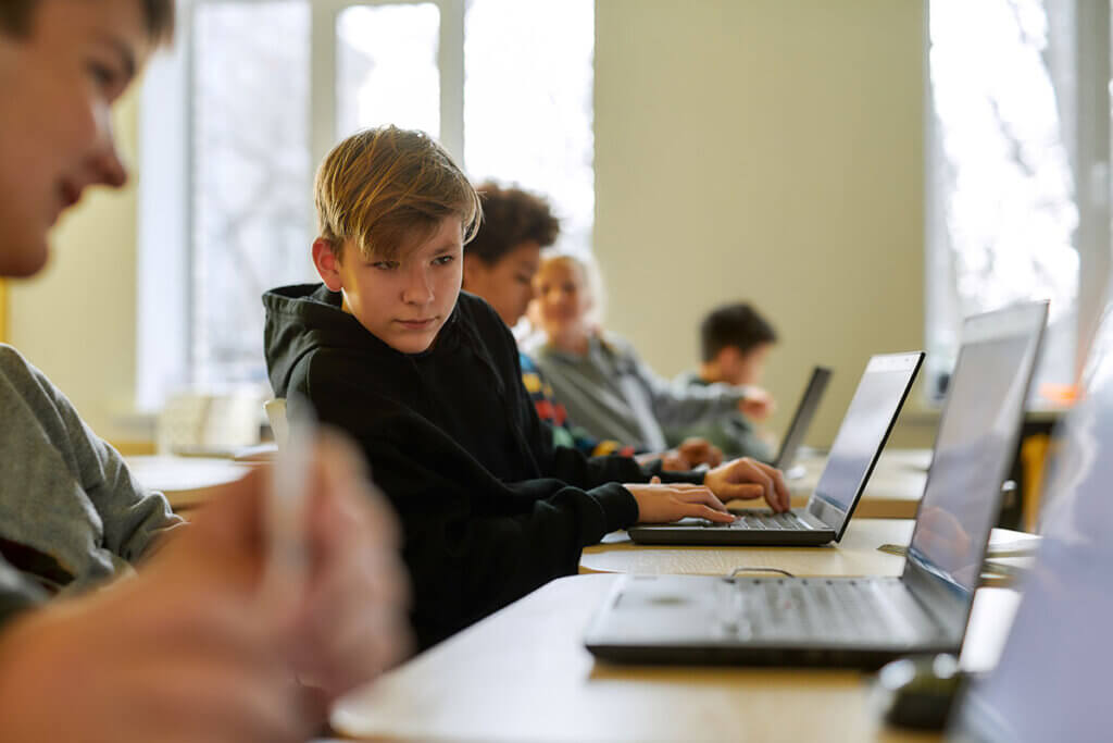 pupil on laptop looks to neighbour for advice
