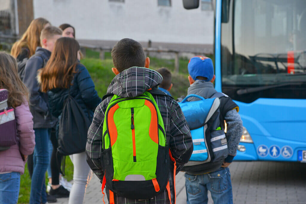 schoolchildren with neon backpacks on the way to the school bus