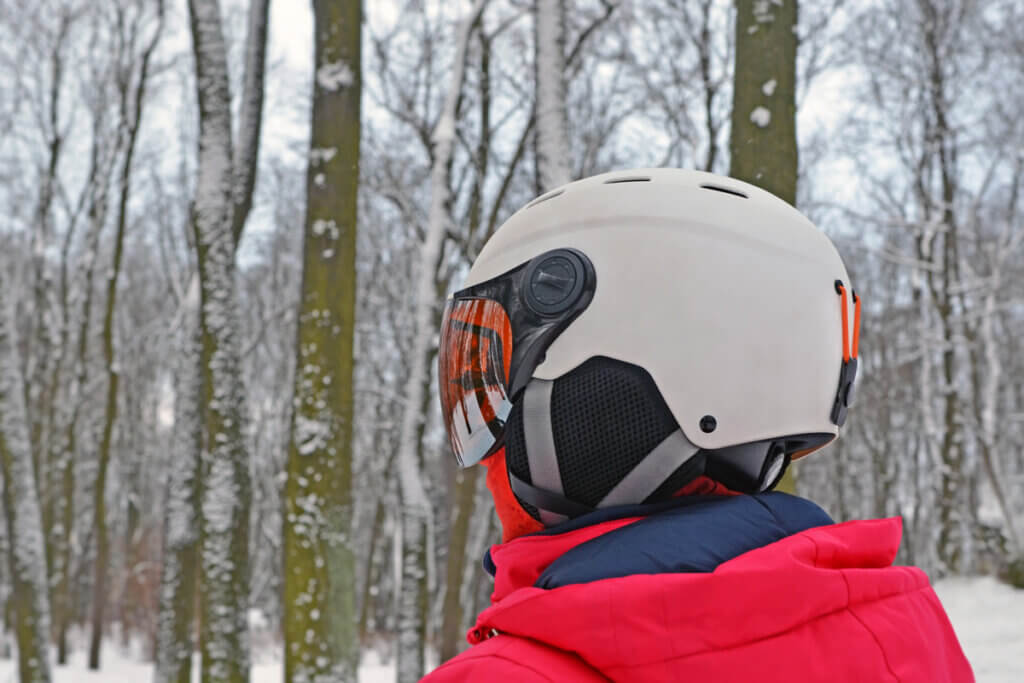 person wearing a ski helmet, standing in the forest