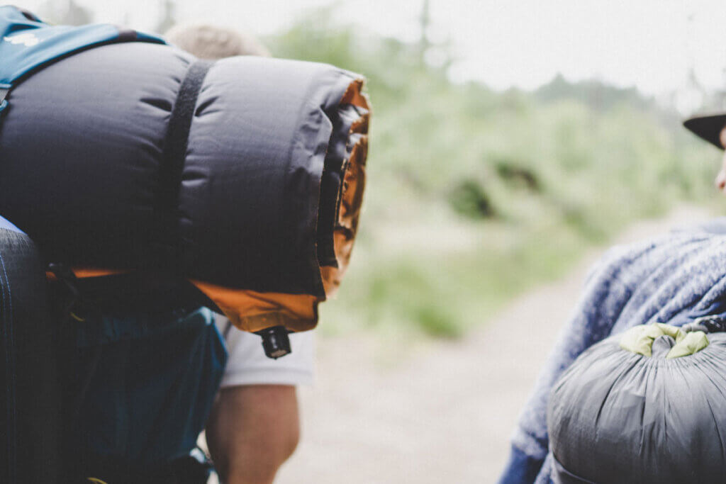 Inflatable sleeping mat attached to a backpack