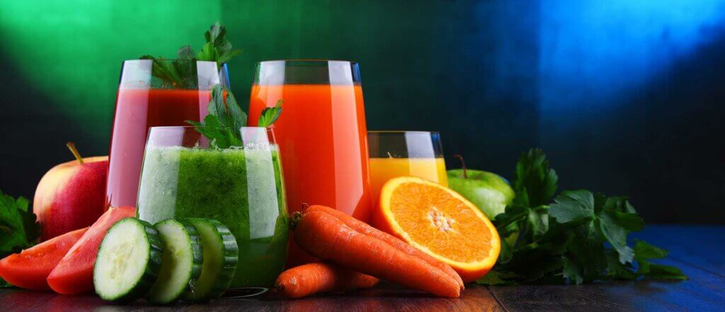 vegetables fruits and juice glasses on a colorful background