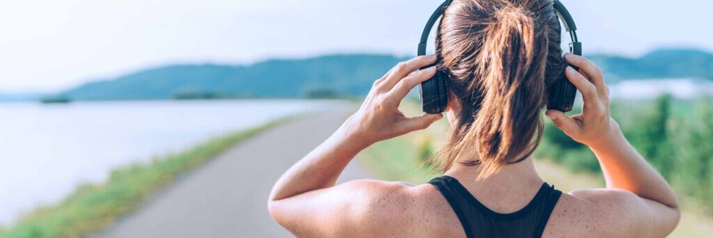 Young woman puts on headphones for sports